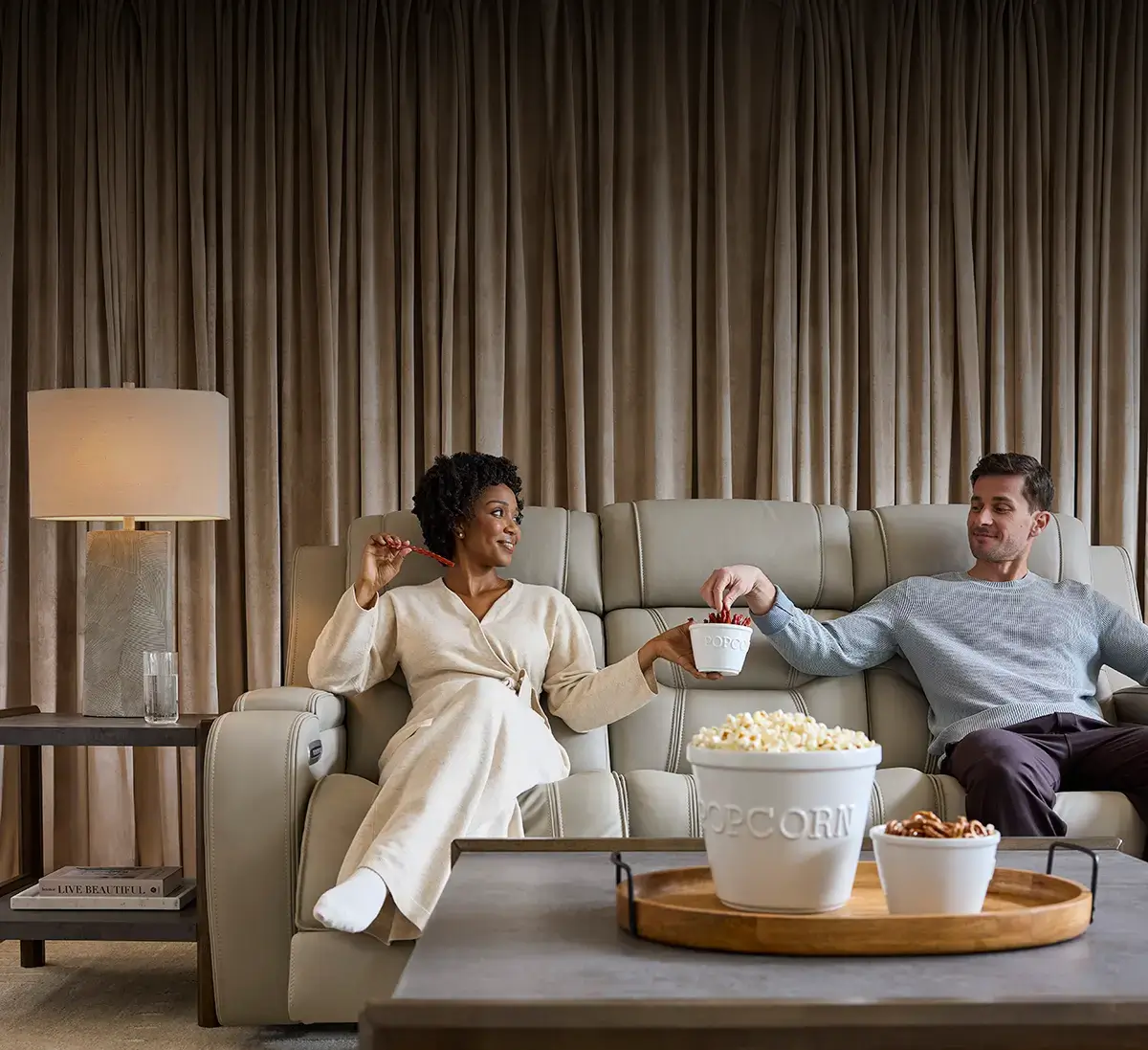 Couple relaxing and eating snacks in an Ashley sofa